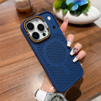 A navy blue textured phone case with a built-in power bank port, held by a hand with long decorated nails over a wooden table background.