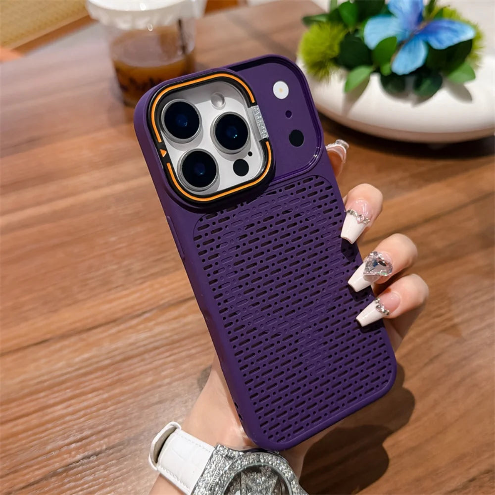 A hand holding a purple textured phone case with a raised camera bumper, shown on a wooden table with a blurred background of a plant and drink.
