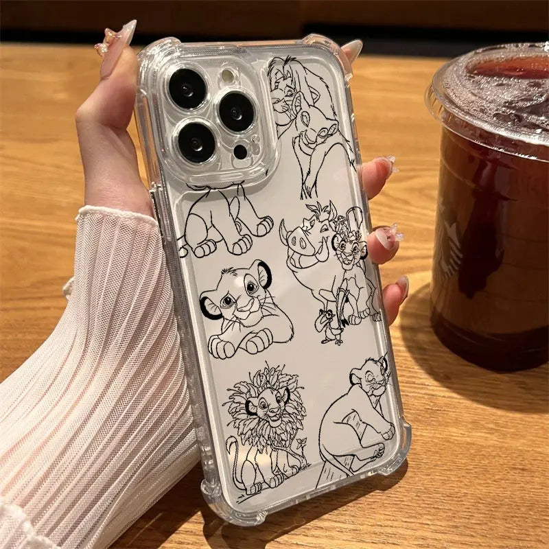 A hand holding a clear iPhone case decorated with black line art illustrations of Disney's The Lion King characters, set against a wooden table with an iced coffee in the background.