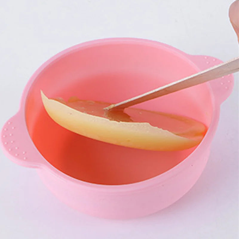 silicone wax warmer with wooden spatula stirring melted pink wax for smooth hair removal waxing